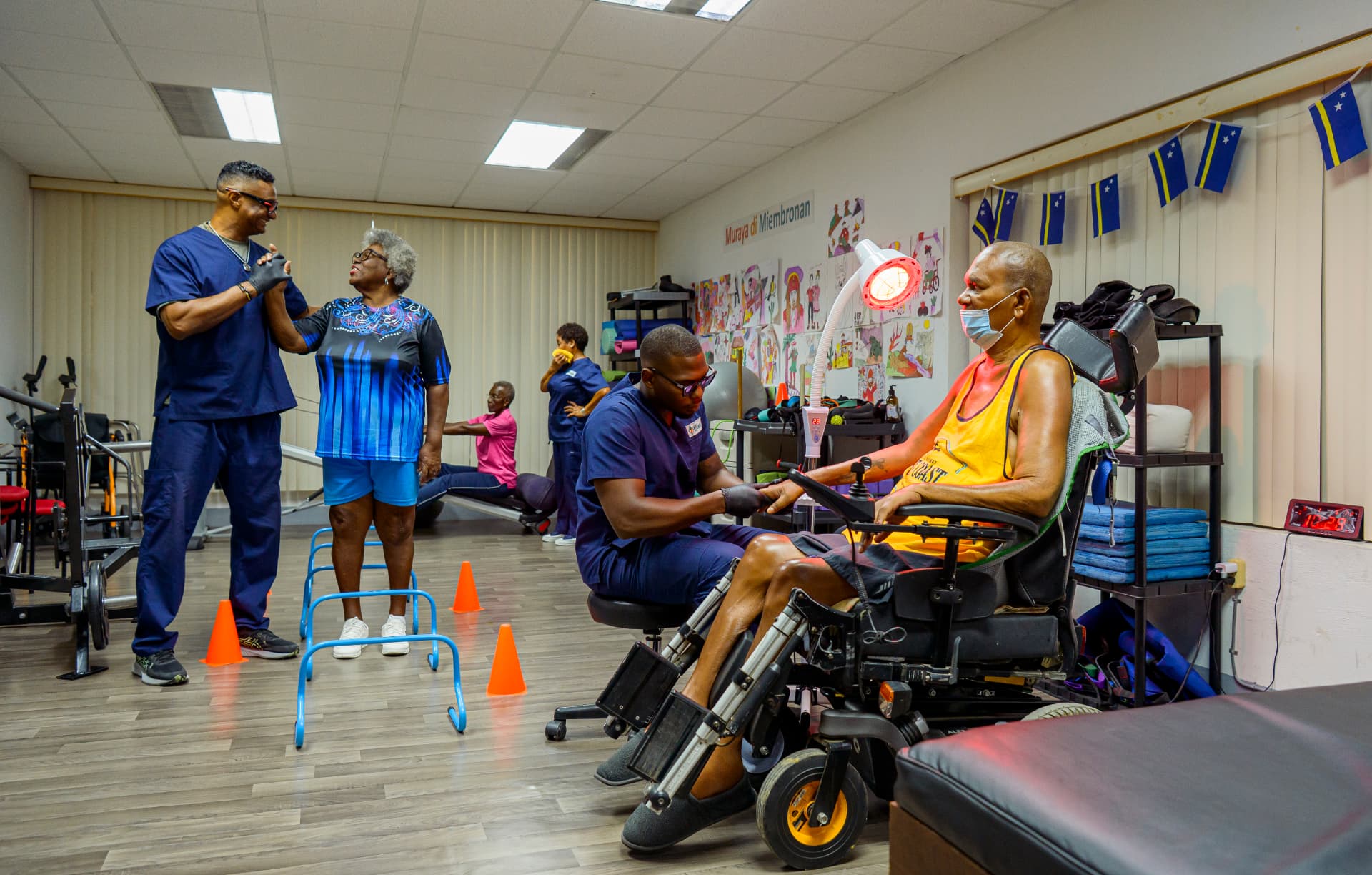 Trainernan di AP Center ta guia klientenan durante un seshon den e sala di ehersisio.
