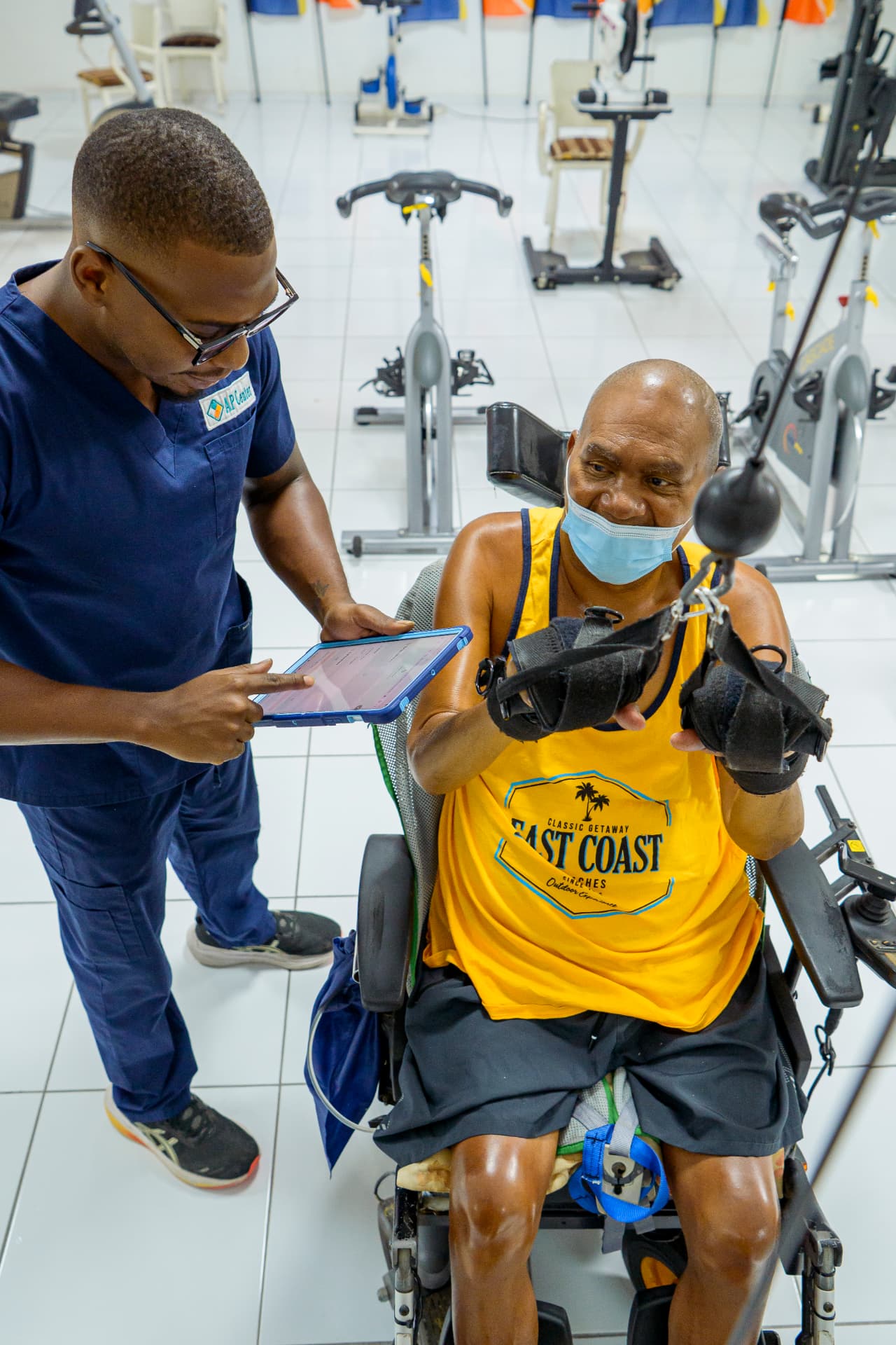 An AP Center trainer logging a client's session on a tablet while the client trains.